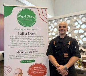 Restaurant chef standing next to banner with restaurant information