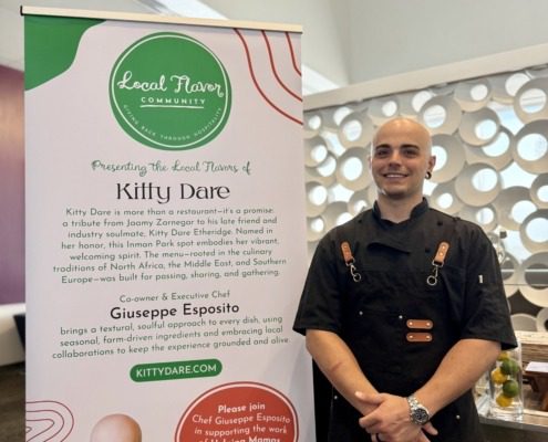 Restaurant chef standing next to banner with restaurant information
