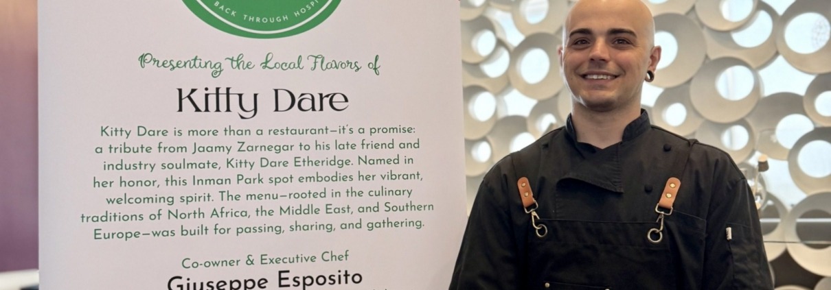 Restaurant chef standing next to banner with restaurant information