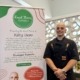 Restaurant chef standing next to banner with restaurant information